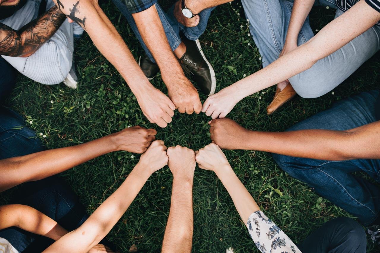 Grupo de personas con los puños unidos en señal de comunidad